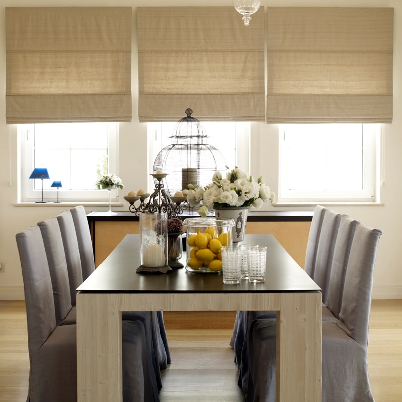 These Paneled Romans are both functional and beautiful. Here we use a natural linen fabric to compliment the rustic look of the dining room. These Roman shades are lined and interlined to give added insulation. Off to the right we compliment the one way sliding door with sheers and side panels. Take a look at the chairs, we can do complimentary full seat covers.